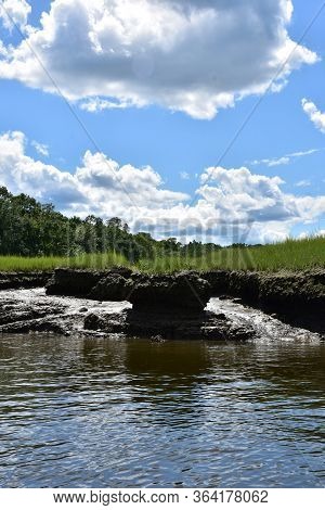 Thick White Clouds Over A Mud Flat On A Tidal Marsh.