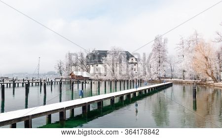 Jetty On Lake Attersee And Typical Architecture On A Snowy Winter Day