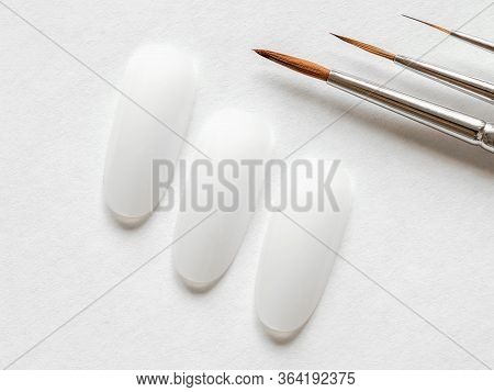 Creative Manicure Concept. Clean Tips And Paint Brushes Of Different Sizes For Manicure On A White B