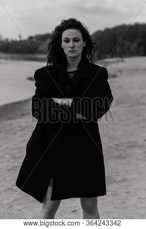 Confident Woman In The Coat Standing On The River Bank With Her Hands Crossed