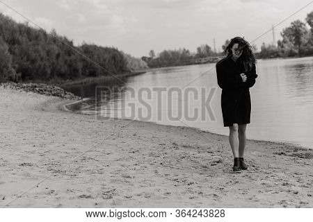 Woman In The Coat Walking Along The River Bank