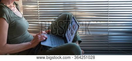 COVID-19 Stay home, Woman self isolated at home working on laptop by window