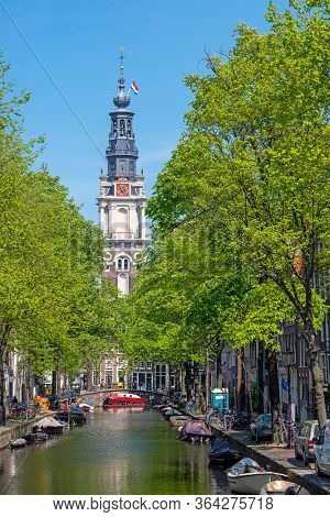 City scenic from Amsterdam in spring in the Netherlands with the South Church (Zuiderkerk) at kings day with the national flag and streamer