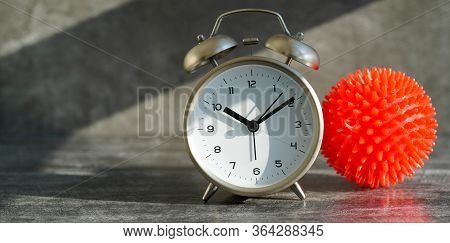 Covid-19 Model And Alarm Clock On A Gray Background. Who Launches New Official Name For Coronavirus 