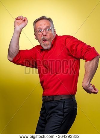 Funny Senior Man Pretending Showing The Muscles With Open Mouth. Making Funny Faces And Jestures.