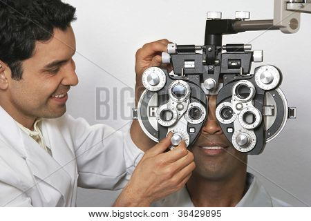 Mandlige optometrist med phoropter når de undersøger patienten
