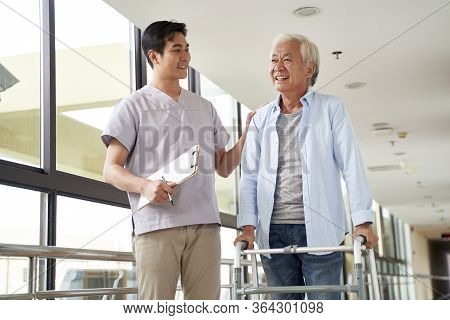 Happy Senior Asian Woman Talking To Physical Therapist In Rehab Center