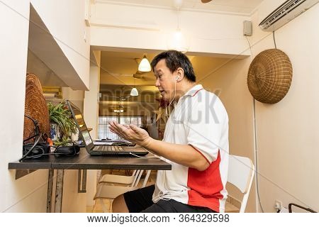 Matured Asian Business Man Raises Both Hands In Stressful Expression In Work From Home Video Confere