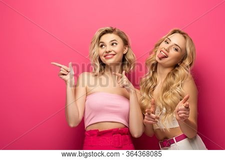 Smiling Blonde Friends Pointing With Finders On Pink Background