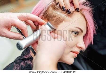 A Barber Shaves Temple Woman Pink Hair With Electric Shaver In Beauty Salon, Close Up Hairdresser Sh