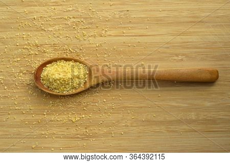 Dry Cracked Wheat Daliya Grains In Wooden Spoon, On Bamboo Cutting Board