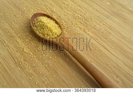 Dry Cracked Wheat Daliya Grains In Wooden Spoon, On Bamboo Cutting Board