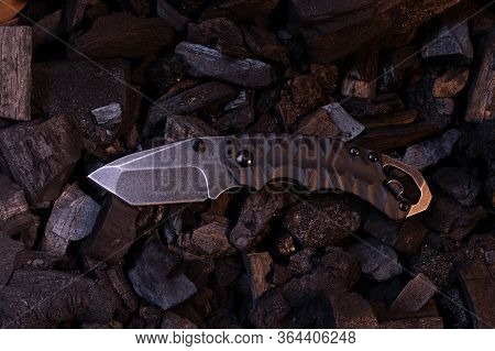 A Small Pocket Knife With A Tanto Blade. Warm And Cold Light.