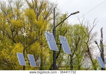 Street Electricity By A Small Windmill And Solapanels In City Against Buildings In Daytime. Concept 