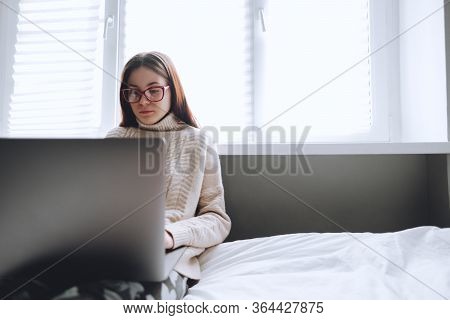 Remote Work At Home, Female On The Bed During The Day Working With A Laptop, Looking On The Screen.