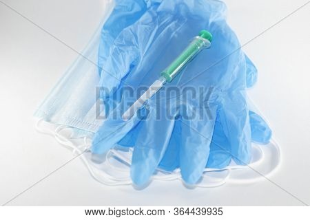 Disposable Blue Medical Mask, Gloves And Syringe On A White Background
