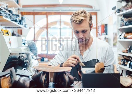 Shoemaker putting glue on sole of a shoe to fix
