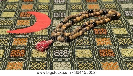 Muslim Prayer Beads On The Prayer Mat With The Crescent Symbol. Islamic And Muslim Concepts
