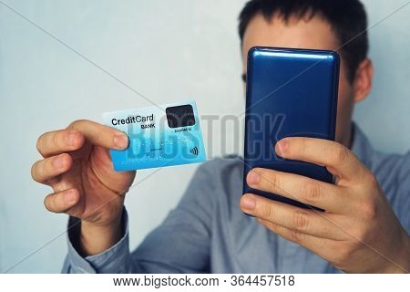 Cropped Shot Of Male In Shirt Making Online Payment Via Plastic Card And Smart Phone. Unrecognizable