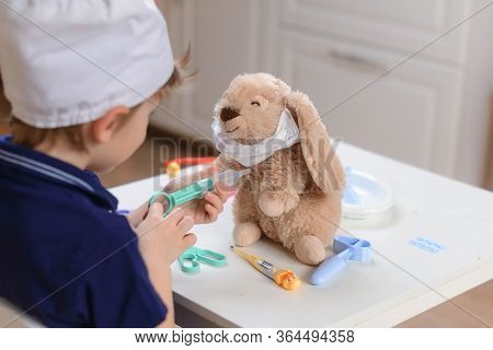 A Little Boy Plays A Doctor And Injects A Toy With A Hare So That He Can Recover From The Coronaviru