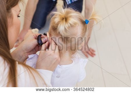 Hearing Aid In Baby Girls Ear. Toddler Child Wearing A Hearing Aid At Home. Disabled Child, Disabili