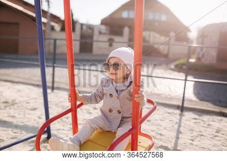 Adorable Little Girl On The Swing Set In Playground. Happy Little Girl Have Fun. One And Hulf Year G