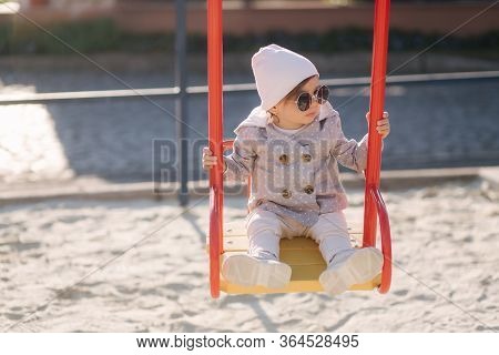 Adorable Little Girl On The Swing Set In Playground. Happy Little Girl Have Fun. One And Hulf Year G