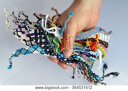 Male Hand Holding Woven Multi-colored Friendship Bracelets Isolated On White Background