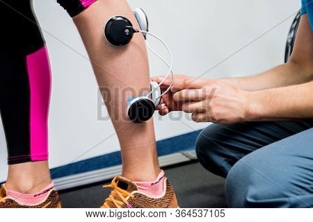Physical Therapist Install Electrostimulator On The Muscles Of The Legs.