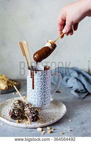 Frozen Banana On A Stick Covered With Dark Chocolate And Crumbs Of Nuts. A Quick, Delicious Dessert 