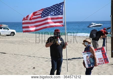 Laguna Beach, California / USA - May 2, 2020. #OpenUpCa. Various people smile, hold signs, flags, wave and cheer as they protest the Coronavirus Lock Down in Laguna Beach, California. 