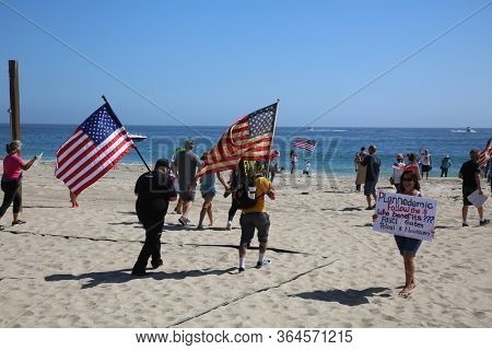 Laguna Beach, California / USA - May 2, 2020. #OpenUpCa. Various people smile, hold signs, flags, wave and cheer as they protest the Coronavirus Lock Down in Laguna Beach, California. 