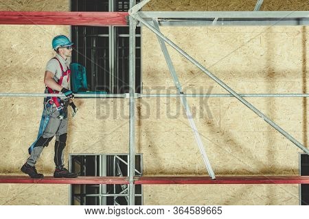 Constrcution Worker Walking On Scaffold To Access Portion Of Building And Perform Needed Work.