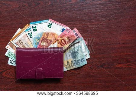 Leather Wallet With Euro Notes On Wood Background. Various Kinds Of Euro Banknotes On Desk With Leat