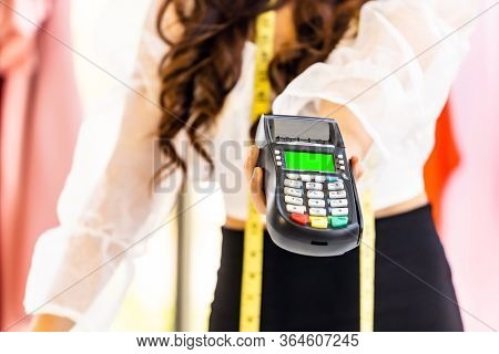 Close-up fashion designer hand hold EDC Machine for customer payment with credit card at her atelier studio as sole owner. Using for entrepreneur startup and consumerism concept.