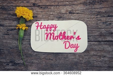 Happy Mothers Day Wish Written On White Paper Note With Marigold Flowers Isolated On Wooden Backgrou