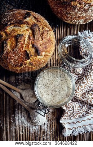 Rye Sourdough Starter In Glass Jar And Homemade Sourdough Bread On A Rustic Wooden Table, Top View