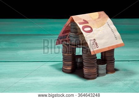 House Made Of Coins And Euro Banknote On Green Table