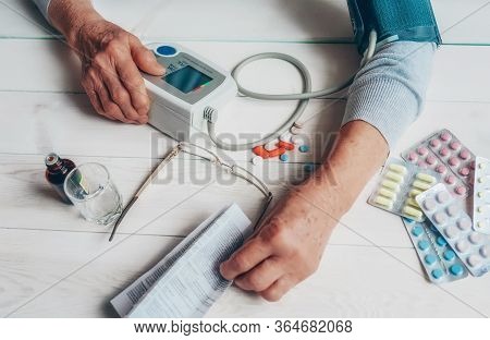 Senior Wrinkled Hand Pushing Back Pills And Thermometer, Dumb-bell On A Table. Another Old Woman Han