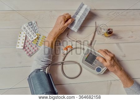 Senior Wrinkled Hands With Blood Pressure Measure Cuff, Medicine Bottle, Glass, Colorful Pills, Ther