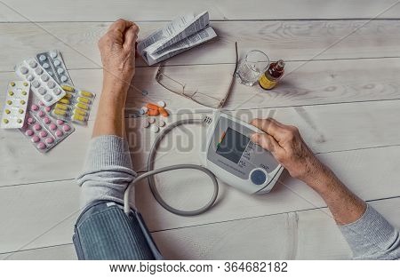 Senior Wrinkled Hands With Blood Pressure Measure Cuff, Medicine Bottle, Glass, Colorful Pills, Ther