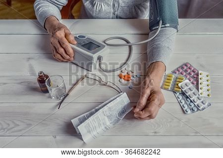 Senior Wrinkled Hands With Blood Pressure Measure Cuff, Medicine Bottle, Glass, Colorful Pills, Ther
