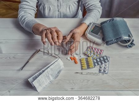 Senior Wrinkled Hands With Blood Pressure Measure Cuff, Medicine Bottle, Glass, Colorful Pills, Ther