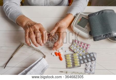 Senior Wrinkled Hands With Blood Pressure Measure Cuff, Medicine Bottle, Glass, Colorful Pills, Ther
