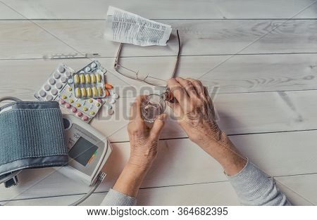 Senior Wrinkled Hands With Blood Pressure Measure Cuff, Medicine Bottle, Glass, Colorful Pills, Ther