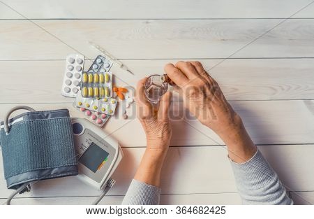 Senior Wrinkled Hands With Blood Pressure Measure Cuff, Medicine Bottle, Glass, Colorful Pills, Ther