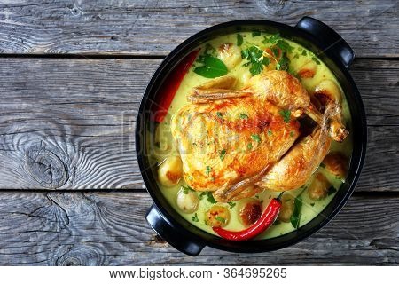Thai Coconut Milk Roasted Chicken And Baby Potatoes With Chili, Kaffir Lime Leaves In A Black Braise