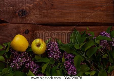 Bright Yellow Apples, Purple Lilac Flowers With Fresh Green Leaves On Wooden Background Flat Lay.col