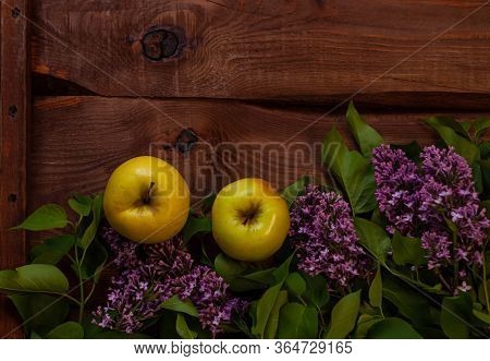 Bright Yellow Apples, Purple Lilac Flowers With Fresh Green Leaves On Wooden Background Flat Lay.col
