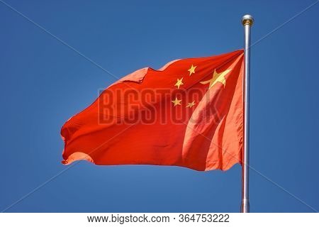 Flag Of The Peoples Republic Of China Against The Clear Blue Sky